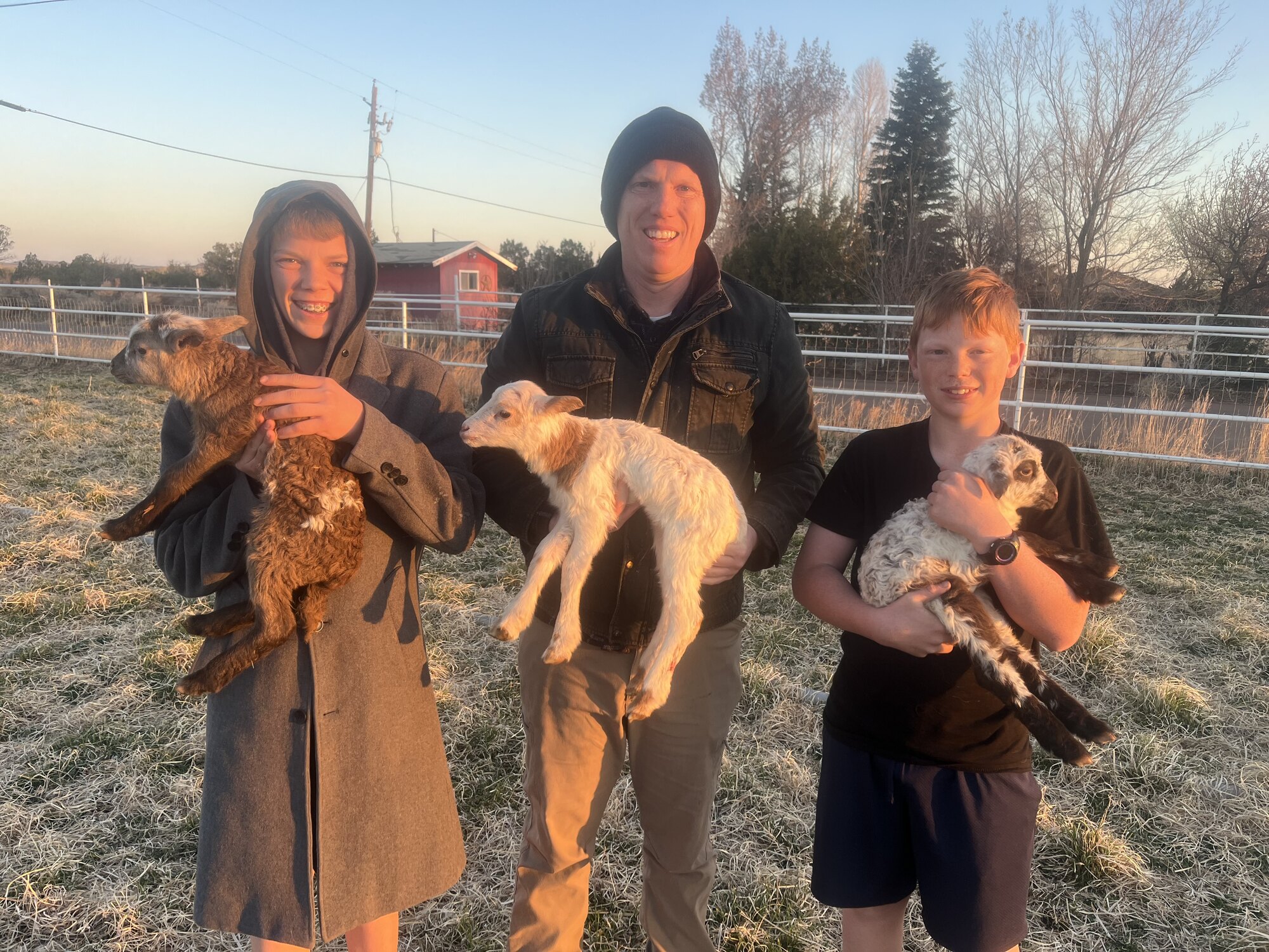 Family members holding newborn lambs on the homestead